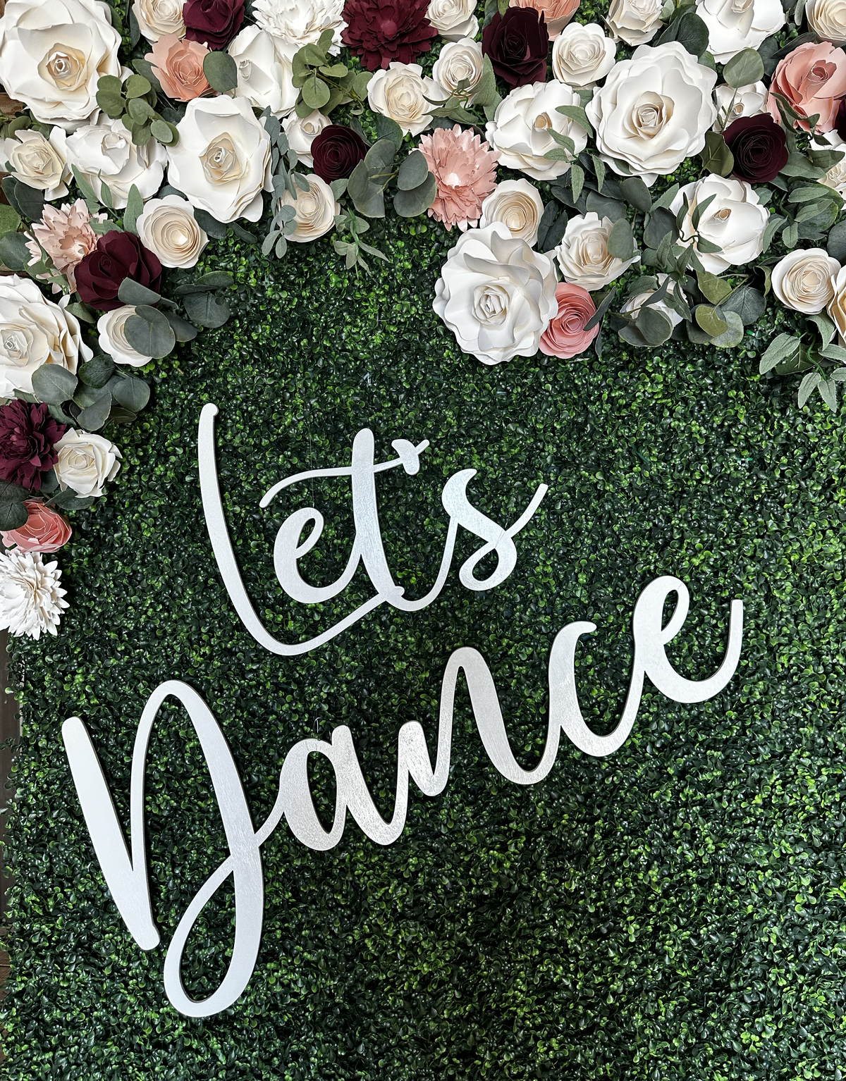 Green hedge wall with flowers and a Let's Dance sign