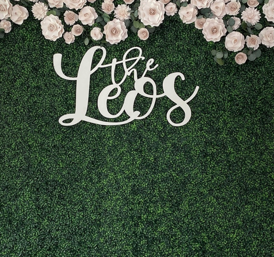 Green hedge wall with white flowers and The Lees sign